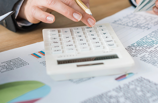 calculator laying on top of documents that have charts on them